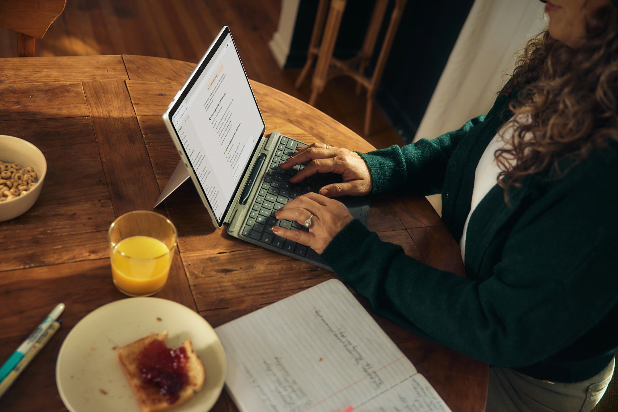 Woman typing on laptop at wooden table with breakfast